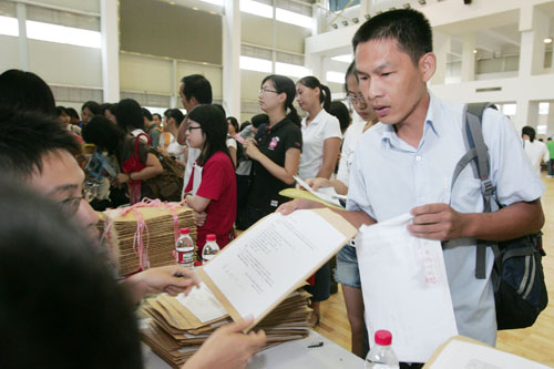 在報(bào)到現(xiàn)場(chǎng)，蔡偉從工作人員手中接過新生報(bào)到材料。  劉暢/攝 